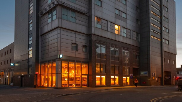 Un edificio moderno con ventanas amplias y una cafetería en la planta baja.