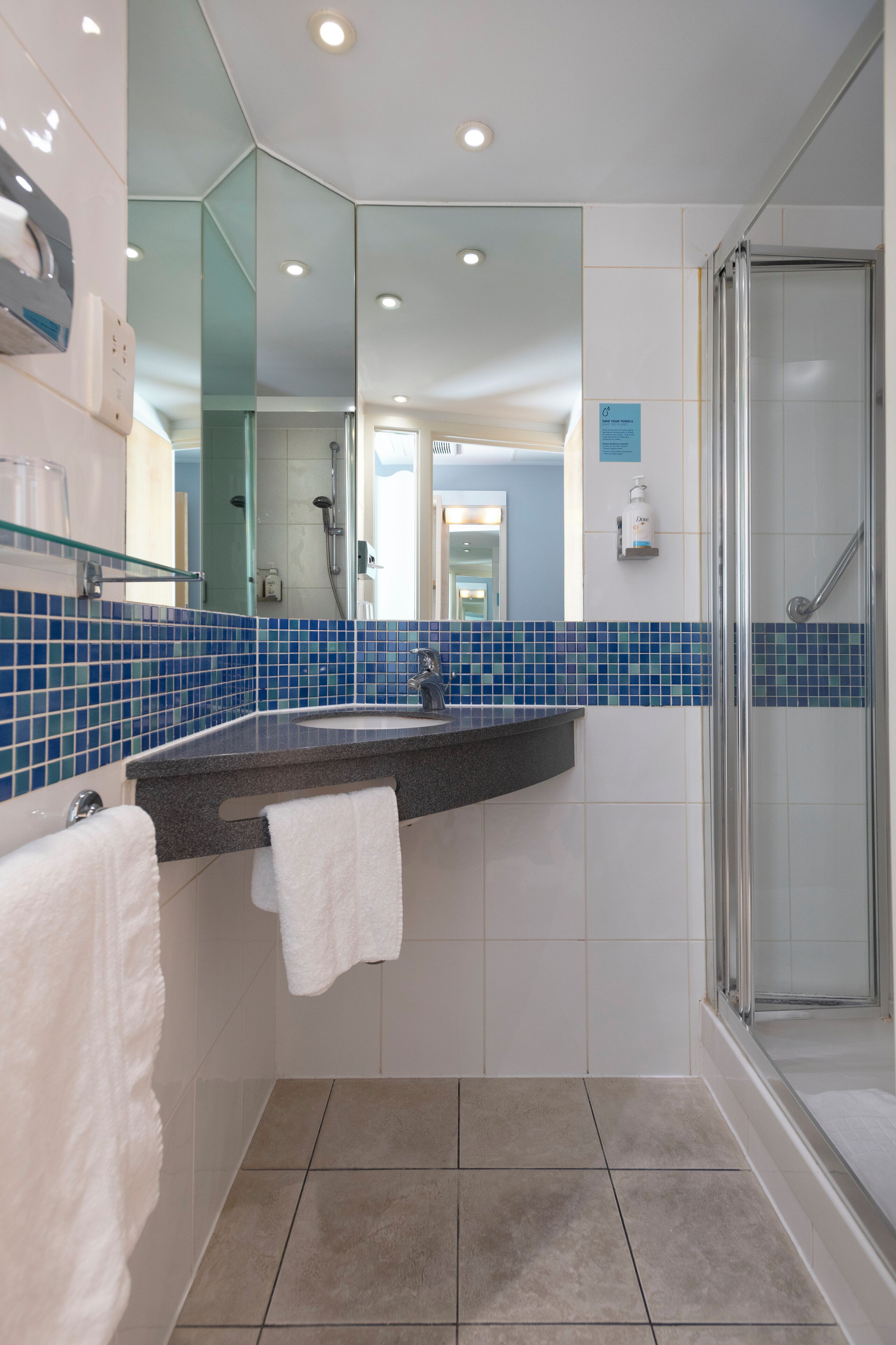 Ein modernes Badezimmer mit Glasdusche, Waschbecken mit Handtuch und Spiegel.