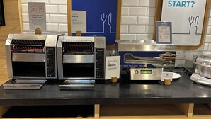 A breakfast station with two toasters, a self-serve pancake press, and a sign indicating availability on request. - Holiday Inn Express Swindon City Centre by IHG (Swindon)