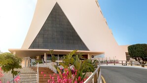 A tall, modern hotel with a unique triangular design and a prominent 'RH' logo.