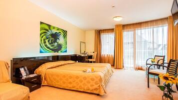 A hotel room with a large bed, a desk, a chair, and a TV.