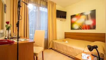 Une chambre d’hôtel comprenant un lit, un bureau avec un téléphone, une chaise, un téléviseur fixé au mur et un tableau.