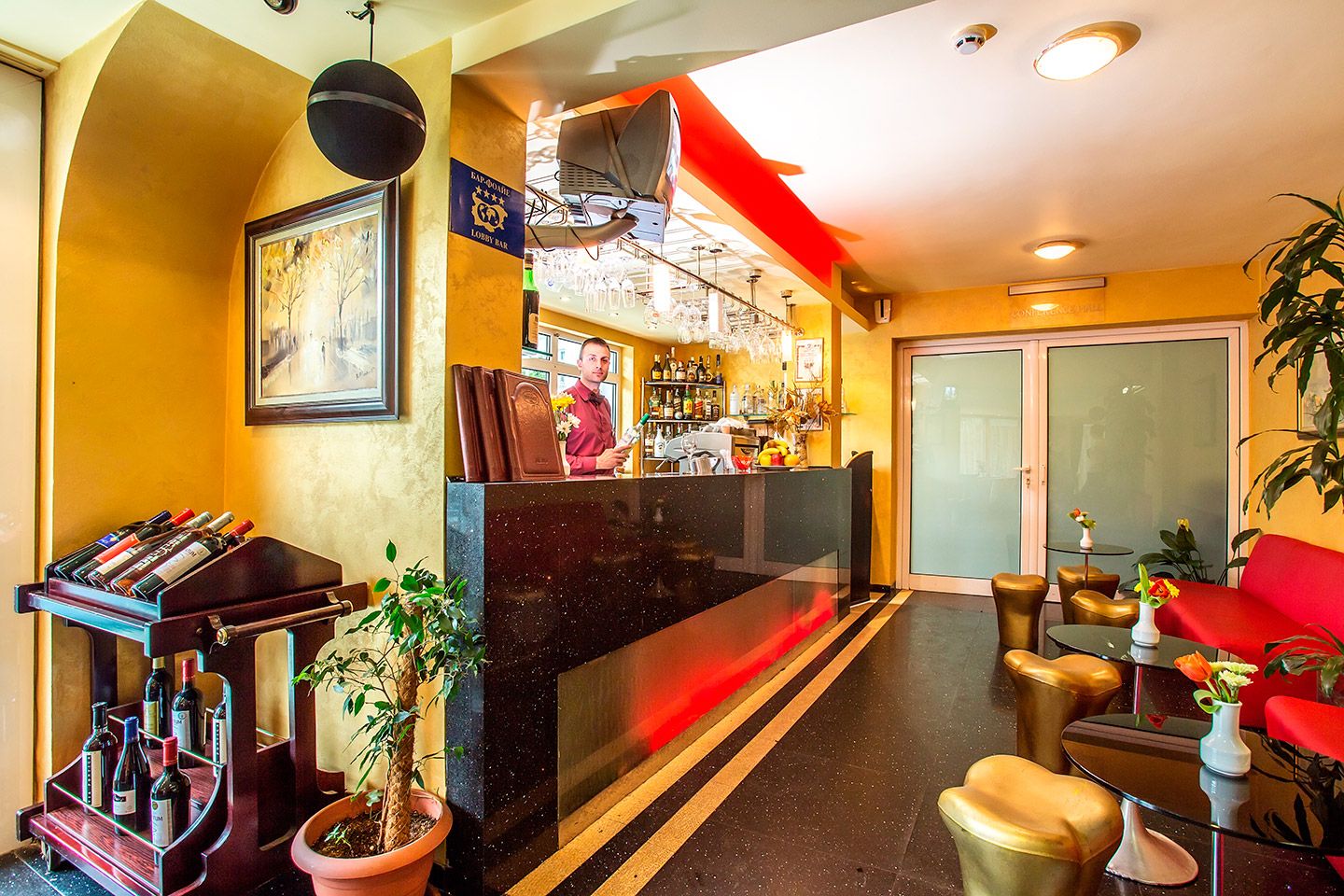 A lobby with a reception desk, a bar area, seating, and a large window.