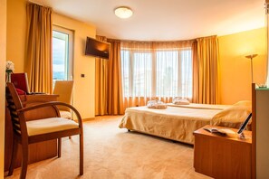 A hotel room with a bed, a desk, a chair, a TV, and a lamp. - Hotel Europe (Sofia)