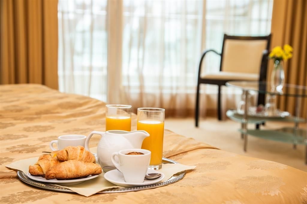 Un desayuno servido en la cama con croissants, café y zumo de naranja.