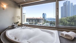 A modern bathroom with a large bathtub, a window with a city view, and a towel rack. - Taxim Suites Residences Istanbul (Istanbul)