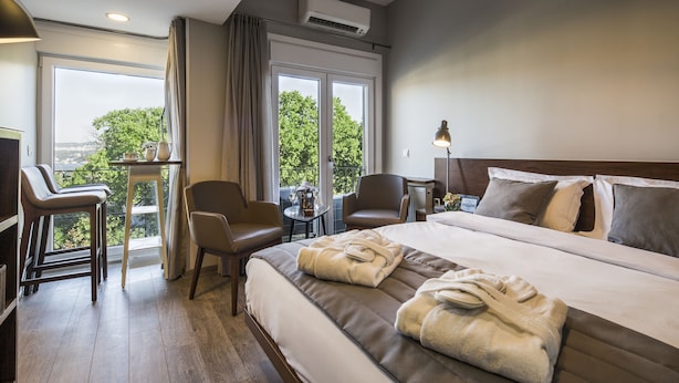 A hotel room with a large bed, a desk, a chair, and a view of the outdoors. - Taxim Suites Residences Istanbul (Istanbul)