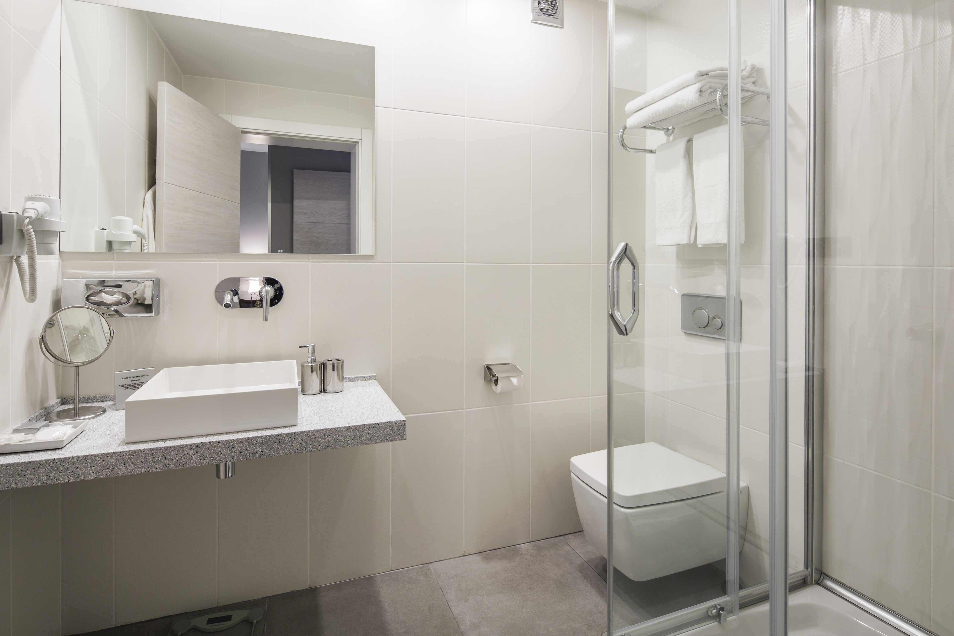 A modern bathroom with a glass-enclosed shower, a white sink, and a toilet.