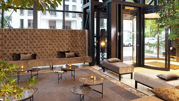 A modern lounge area with a sofa set, round tables, and a glass partition.