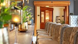 A reception area with a long counter, several upholstered chairs, and a wooden door leading to another room.
