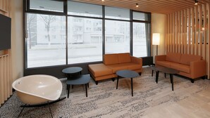 Un salon moderne doté d’une grande fenêtre, de deux canapés, d’une table ronde et d’une baignoire originale.