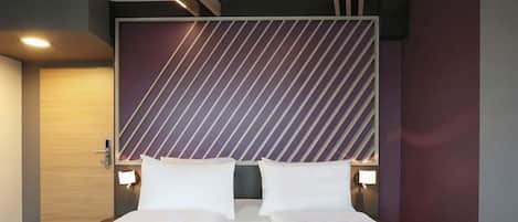 A hotel room with a large bed, two bedside tables, and a modern headboard with diagonal stripes.