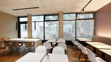 Una sala de conferencias moderna con ventanas amplias, mesas y sillas blancas.