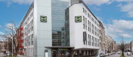 Un hotel tipo bed and breakfast moderno con fachada de vidrio, varios pisos y una entrada destacada.