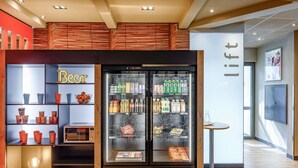 Máquina expendedora de bebidas y snacks, con un rótulo que dice 'Cerveza' y un letrero de 'ascensor', en un interior moderno.