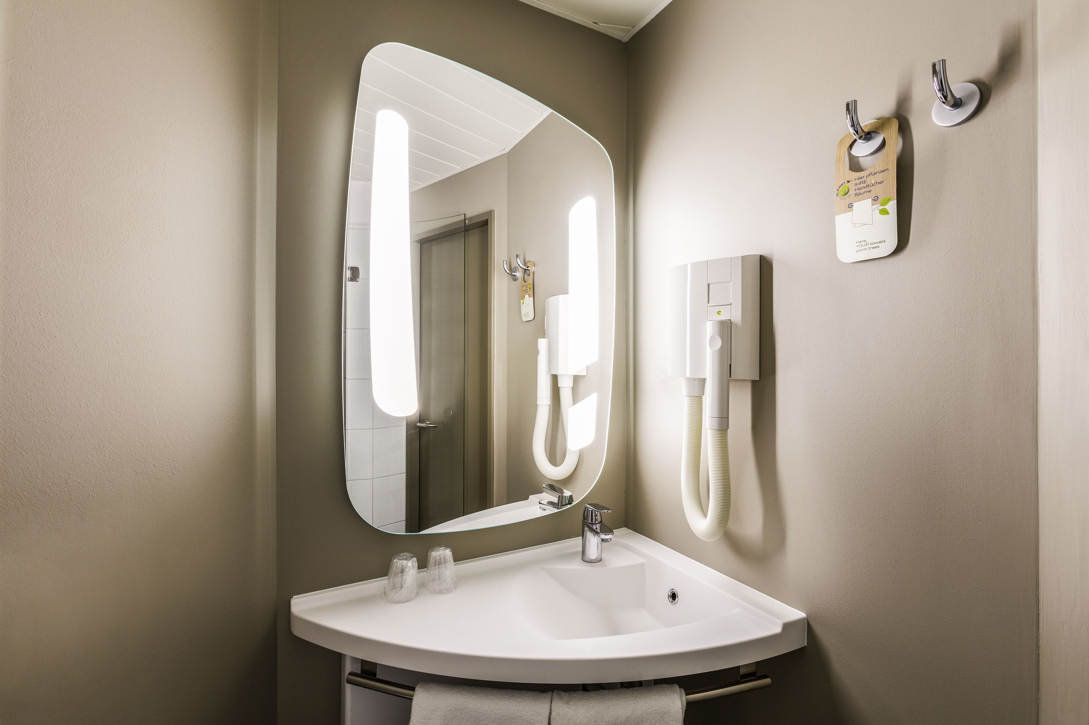 A bathroom with a white sink, a large mirror, and a towel rack.