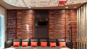 Un área de estar moderna con un sofá, mesas y una pared con listones de madera verticales.