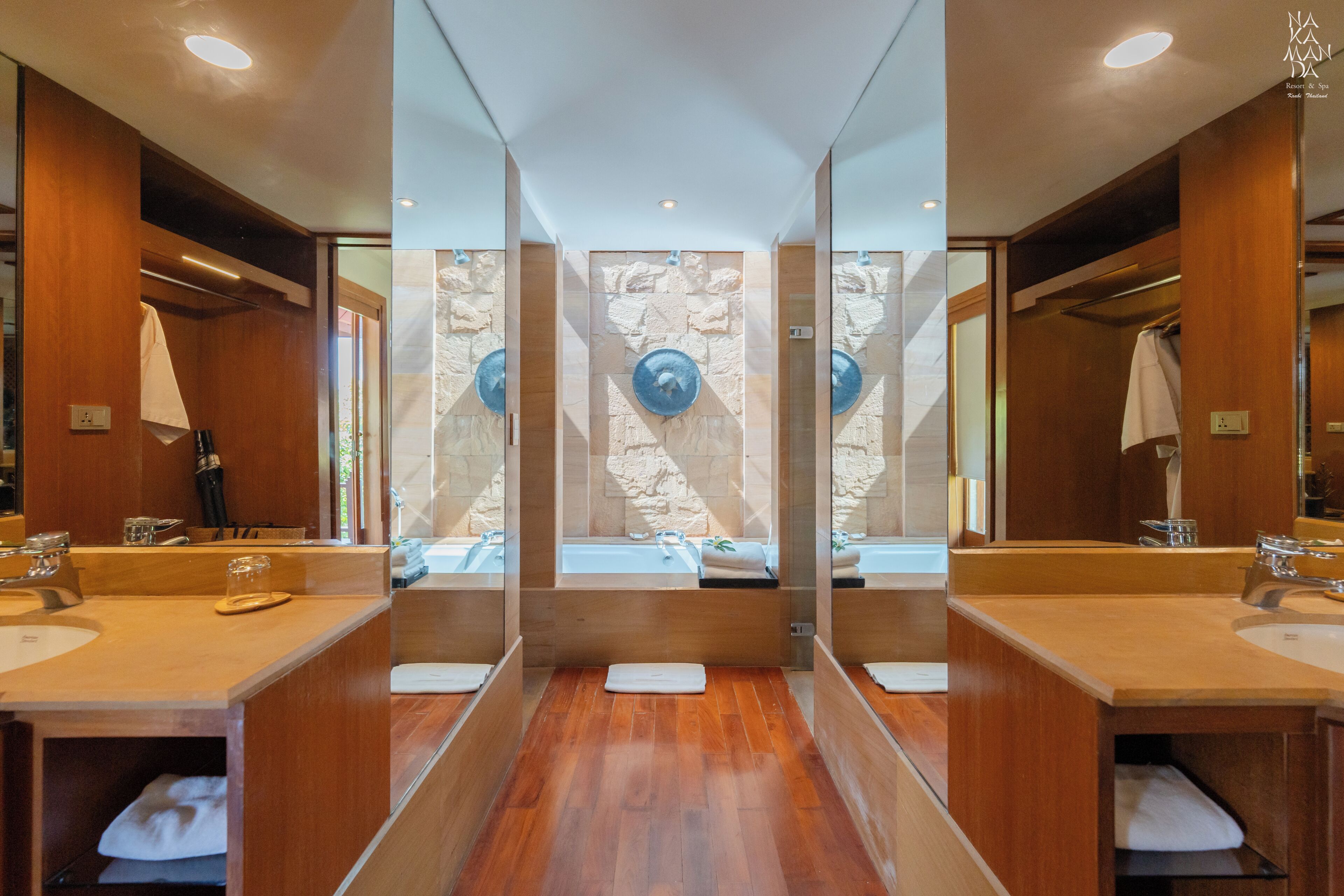 A modern bathroom with two sinks, a large mirror, and a stone wall.