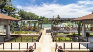Un resort con zonas de estar al aire libre, un camino central y vista al agua.