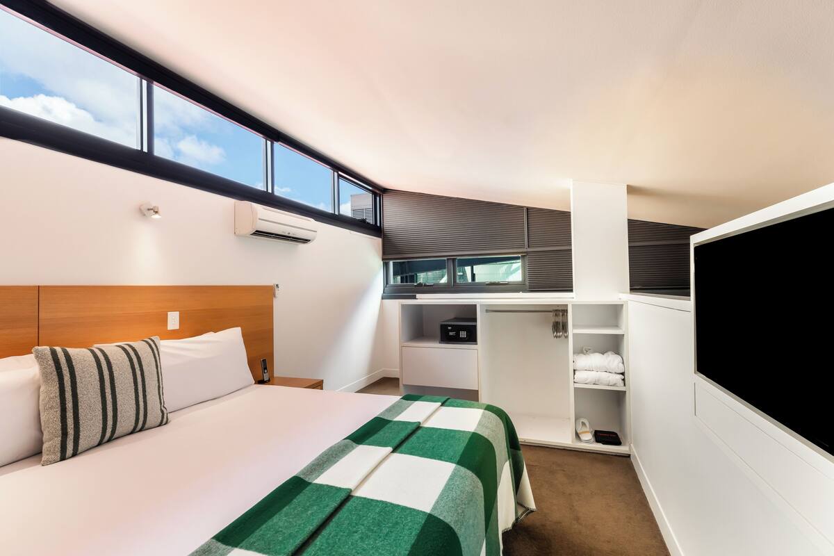 Une chambre d’hôtel équipée d’un lit, d’une télévision, d’un bureau et d’une armoire.