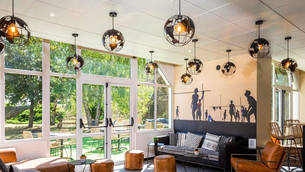 Un interior moderno con grandes ventanales, un mural y una combinación de mobiliario de cuero y metal.
