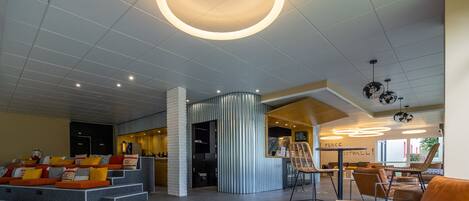 A modern lobby with a circular light fixture, a reception desk, and seating areas.
