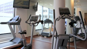 Un gimnasio con cintas de correr, elípticas y una pantalla de televisión.