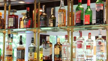 Diverse drankflessen staan uitgestald op planken in een goed verlichte bar.