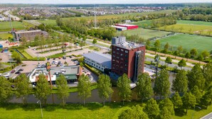 A hotel with a modern design, situated near a sports field and surrounded by greenery.