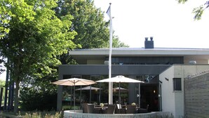 A modern building with outdoor seating and a flagpole.
