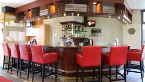 A bar area with a counter, red bar stools, and a television mounted on the wall.