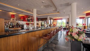 Un área de bar moderna con mostrador de madera, taburetes y un gran centro de flores.