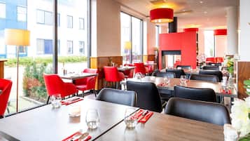 Um restaurante com cadeiras e mesas vermelhas, grandes janelas e design de interiores moderno.