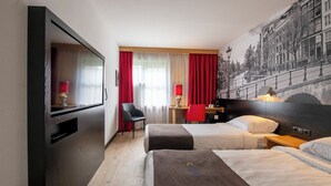 Habitación de hotel con dos camas, un escritorio, una silla y un televisor.
