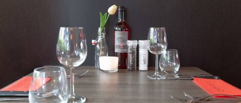 A table set with wine glasses, a bottle of wine, a candle, and condiments.