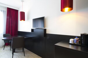 Una habitación de hotel moderna con un escritorio negro, televisión y una cortina roja.