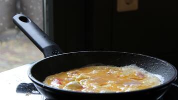 A frying pan on a stove with food cooking inside.