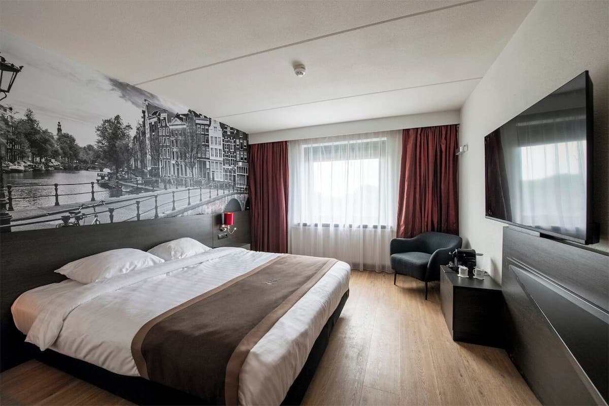 Una habitación de hotel moderna con una cama grande, una televisión de pantalla plana, un escritorio y una silla.
