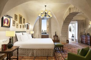 A spacious bedroom with a large bed, a chandelier, and a view through an arched doorway. - Airelles, La Bastide de Gordes (Gordes)