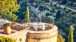 A circular outdoor dining area with a stone wall, metal railing, and tables set for dining. - Airelles, La Bastide de Gordes (Gordes)