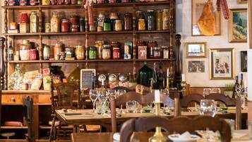 A dining area with wooden furniture, a variety of jars on shelves, and framed pictures on the wall.