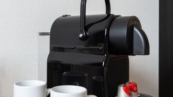 A black espresso machine with two white mugs labeled "Bastion Hotels.NL" on a wooden surface.