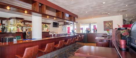 A bar area with a long counter, multiple stools, and a television screen.