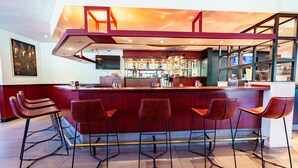 A bar area with a high counter, multiple stools, and a television screen.