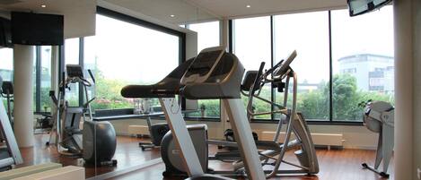 Un gimnasio con cintas de correr, bicicletas estáticas y otros equipos de ejercicio.
