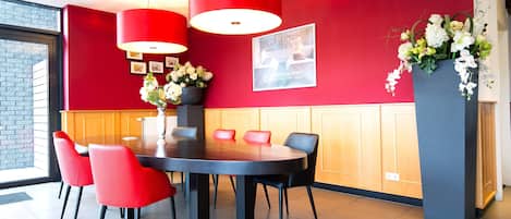 Un comedor moderno con una mesa redonda, sillas rojas y una lámpara colgante roja.