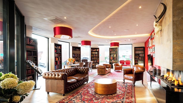 A spacious library with leather sofas, a fireplace, and a large collection of bookshelves.