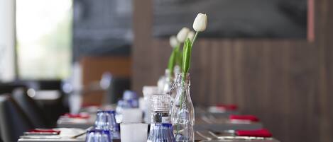 A dining table set with red napkins, clear glass vases with flowers, and a white candle.