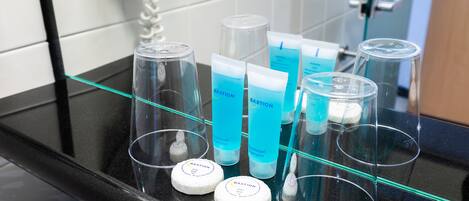 A bathroom counter with various toiletries including bottles and containers, likely in a hotel setting.