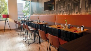 Ein Restaurant mit mehreren Tischen und Sitzgelegenheiten, großen Fenstern und einem Wandgemälde.